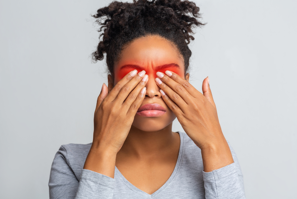 Woman covering eyes with hands, red color emanating from hands