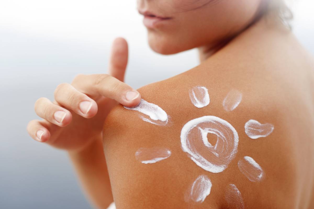 Woman with sunscreen in shape of sun on skin to prevent aging.