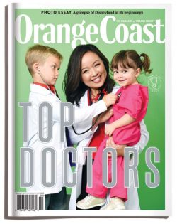 Orange Coast Top Doctors 2018 Cover Doctor in labcoat holding two kids, boy on left holding stethoscope to girl on right, green background